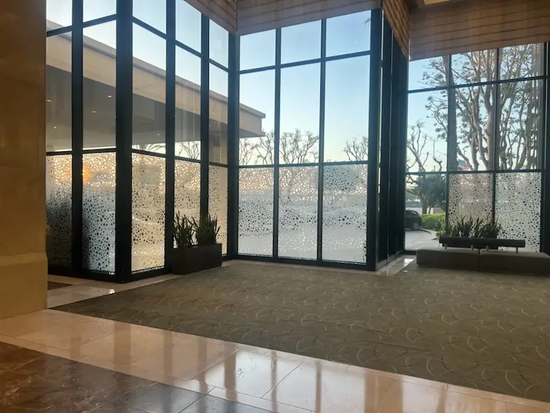 Sunlit indoor area with large glass windows and outdoor view.