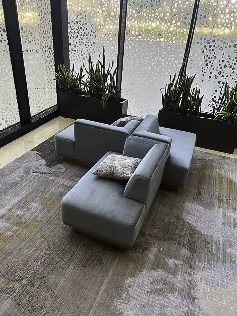 Modern blue sofa with cushions in a glass-walled room.