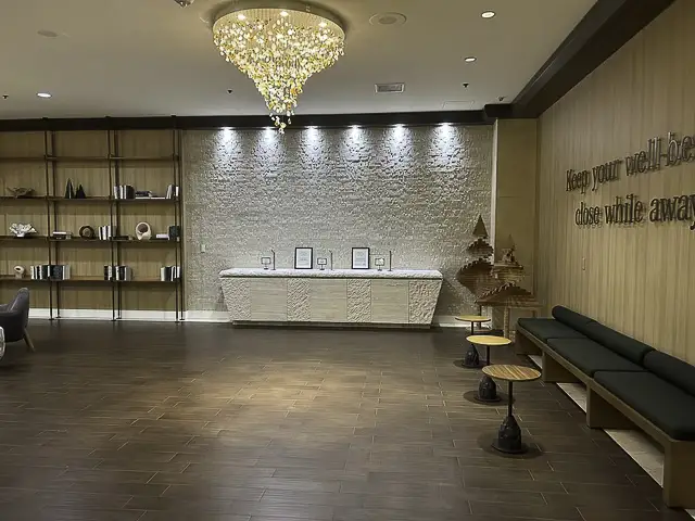 Elegant lobby with chandelier, white stone wall, and seating.