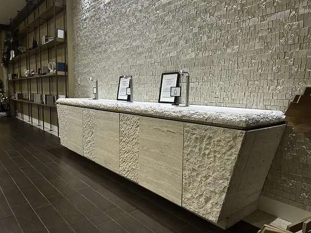 Modern beige textured cabinet with cushioned top against a stone wall.