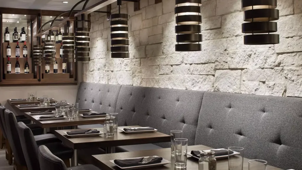 Cozy restaurant seating with tufted gray bench and neatly set tables.
