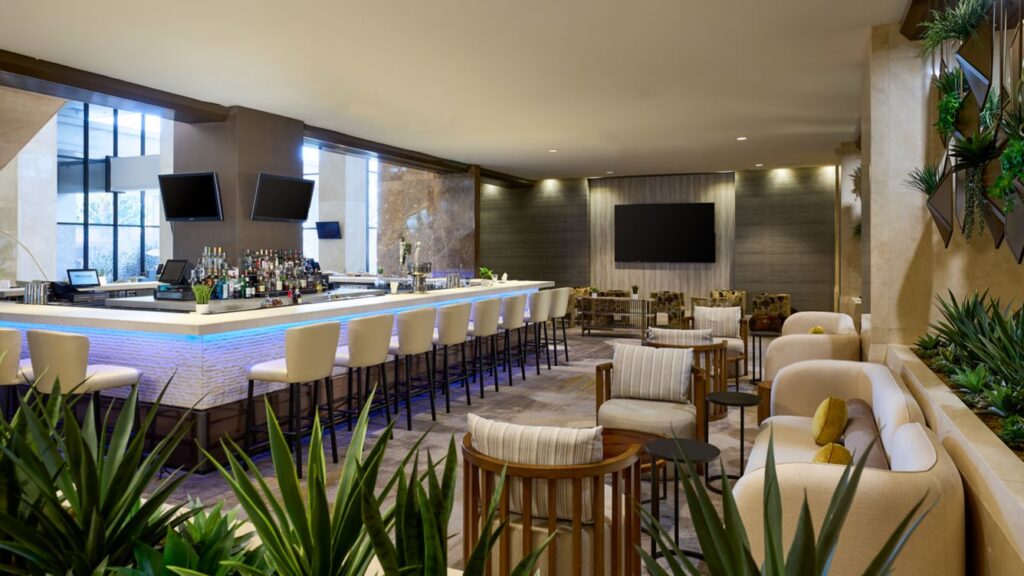 Modern lounge area with bar stools and seating under warm lighting.